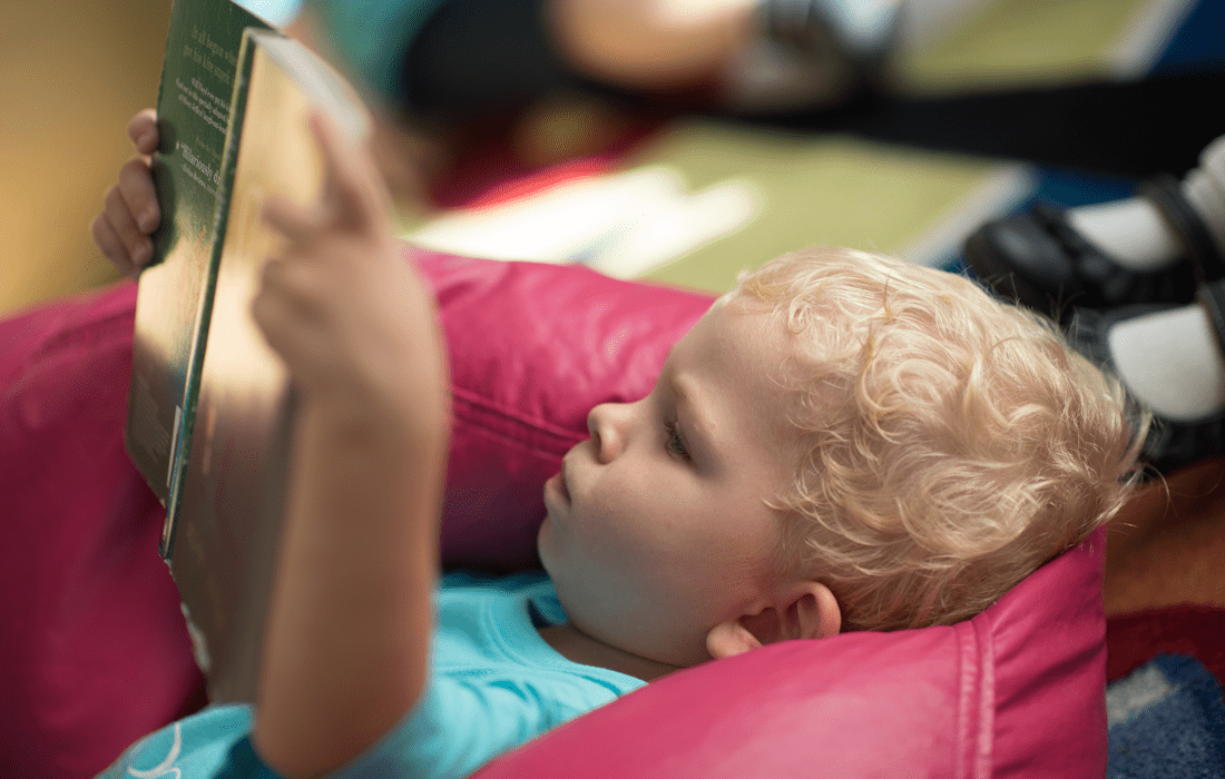 Library: Pre-school student reading in bean bag chair