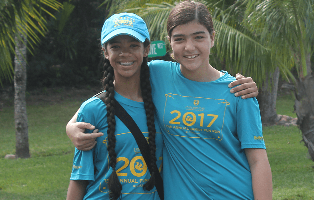 Two students arm in arm at fun run event.